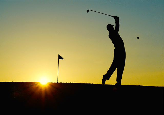 Golfer hitting a golf ball at sunset